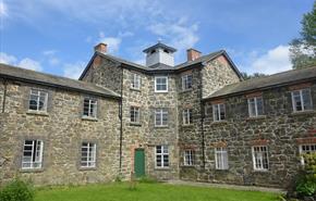 A three-storey building with an octagonal core and a classical cupola, flamked by two-storey wings and built of stone.